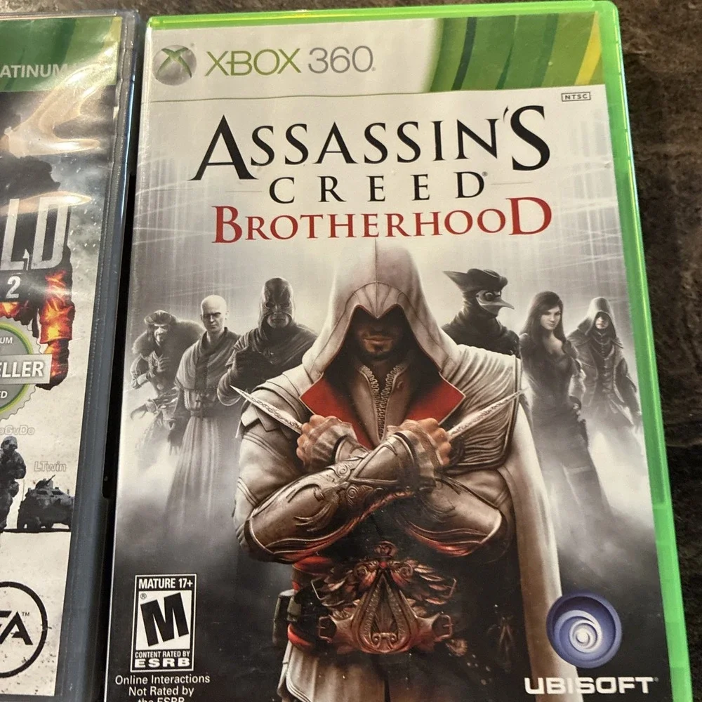Three Xbox 360 Games, Assassin Creed, Battlefield, And Call Of Duty